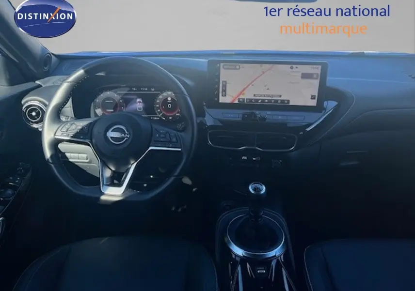 Vue intérieure frontale du tableau de bord du Nissan Juke 2025 avec volant multifonction et écran tactile de navigation.