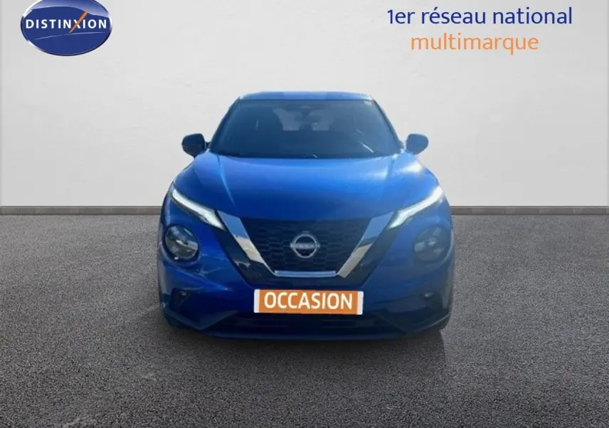 Vue frontale d'un Nissan Juke 2025 bleu magnétique métal avec calandre chromée et phares LED allumés.