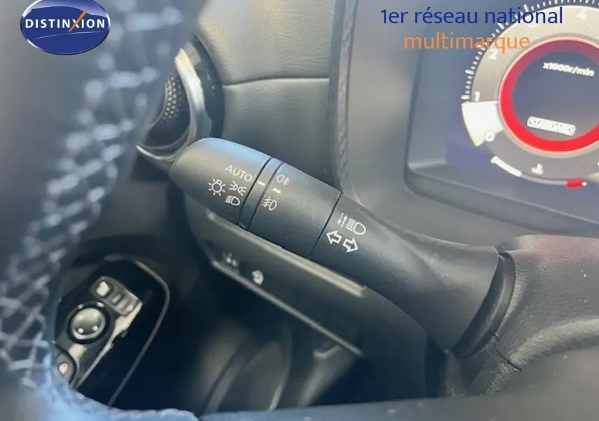 Gros plan sur la commande des feux et clignotants à gauche du volant dans un Nissan Juke bleu magnétique 2025.