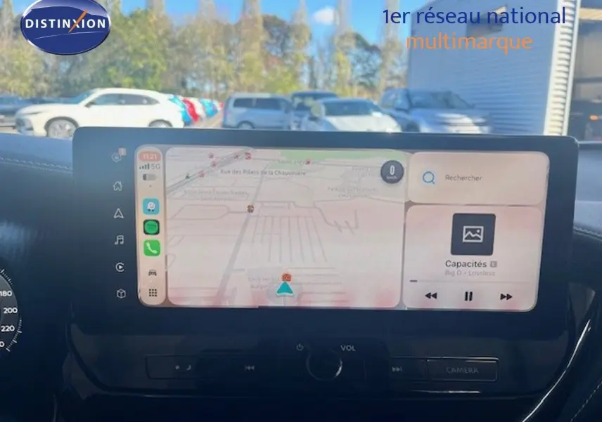 Vue avant du tableau de bord du Nissan Juke 2025 bleu magnétique, avec écran tactile affichant navigation et musique.