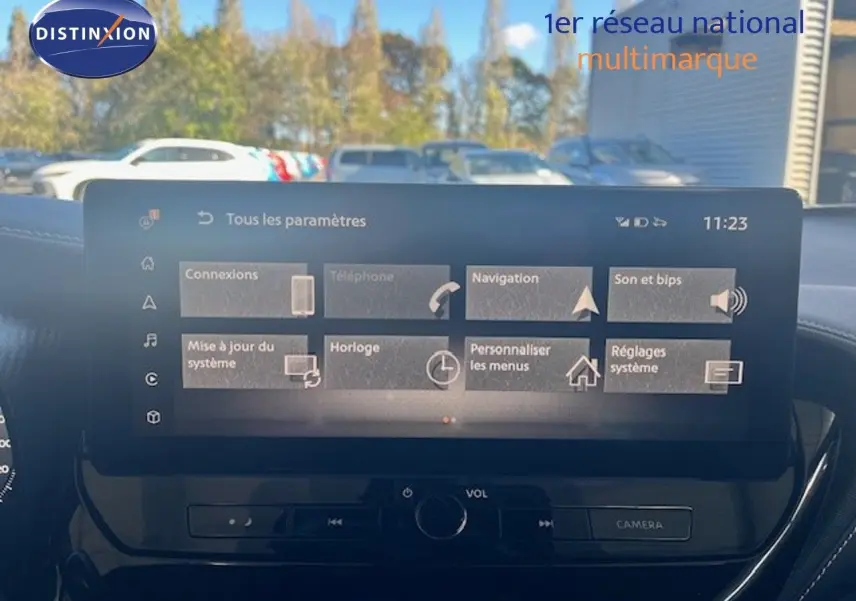 Vue avant intérieure sur l’écran tactile du Nissan Juke bleu magnétique métal 2025 avec commandes de volume et caméra.