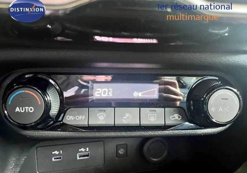 Détail de la console de climatisation automatique du Nissan Juke bleu magnétique, avec affichage digital et commandes rotatives.