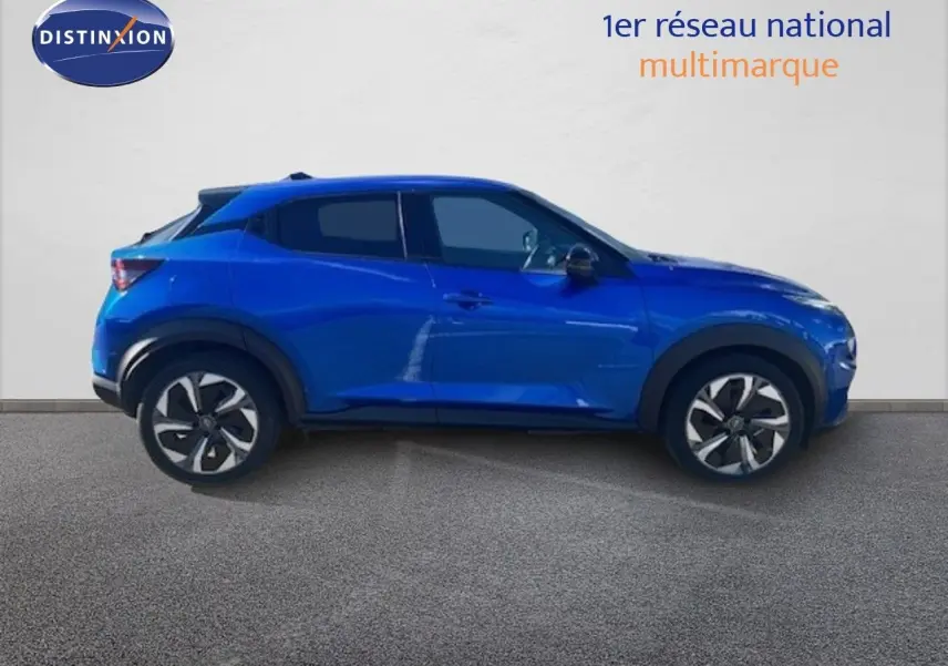 Vue de profil côté gauche d'un Nissan Juke 2025 bleu magnétique métal avec jantes distinctives et lignes modernes.