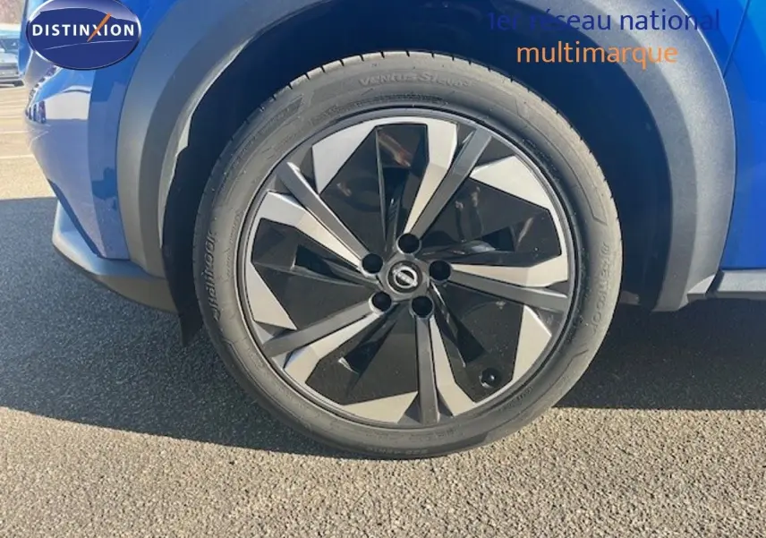 Gros plan sur la roue avant gauche du Nissan Juke 2025 bleu magnétique métal avec jante noire et argentée au design moderne.