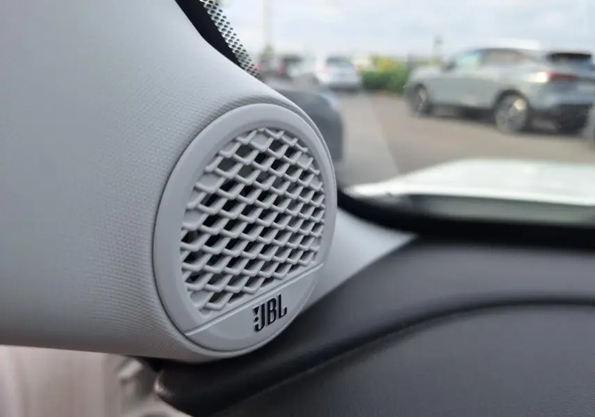 Gros plan sur l'enceinte JBL intégrée au tableau de bord du Jeep Avenger blanc, vue intérieure côté gauche.