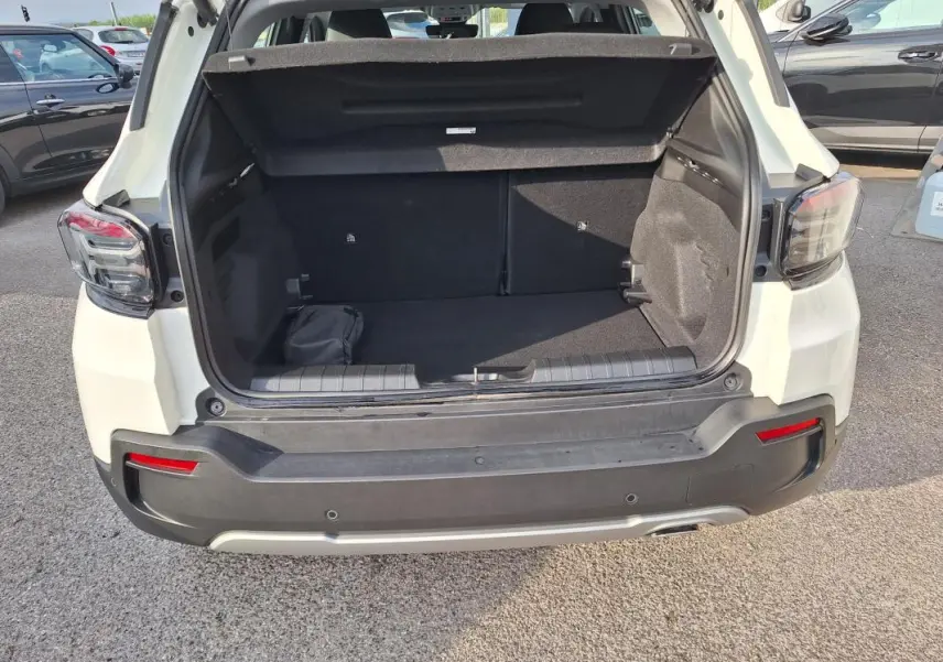 Coffre ouvert vu de l'arrière d'un Jeep Avenger blanc 2025 avec feux arrière LED et pare-chocs noir.