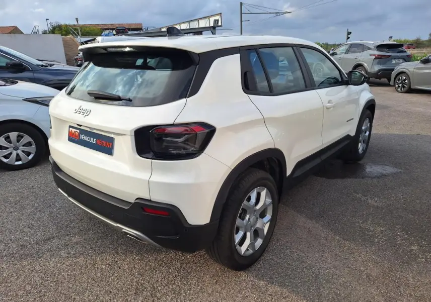 Jeep Avenger blanc en 3/4 arrière droit, avec feux arrière foncés et jantes alliage 17 pouces visibles.
