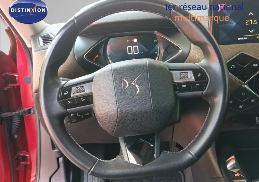 Vue rapprochée du volant en cuir noir du DS3 Crossback rouge, avec tableau de bord numérique et partie centrale du poste de conduite.