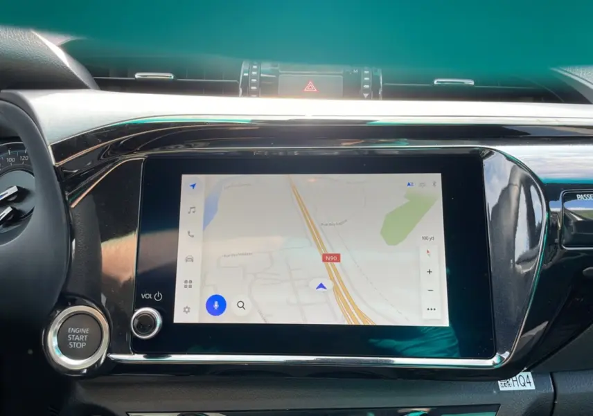 Tableau de bord du Toyota Hilux 2025 avec écran tactile de navigation et bouton start/stop visible.