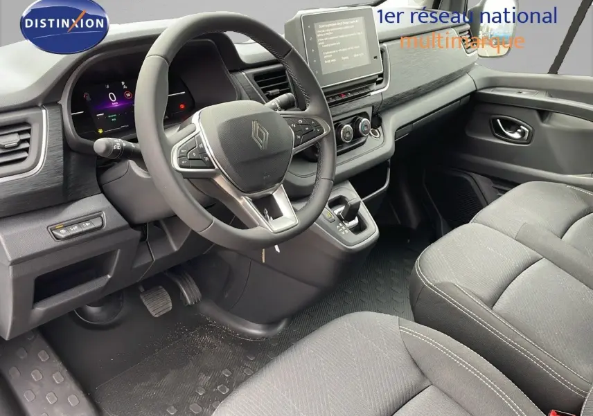 Vue intérieure côté conducteur du Renault Trafic Fourgon 2025 avec tableau de bord moderne et sièges tissu noir.