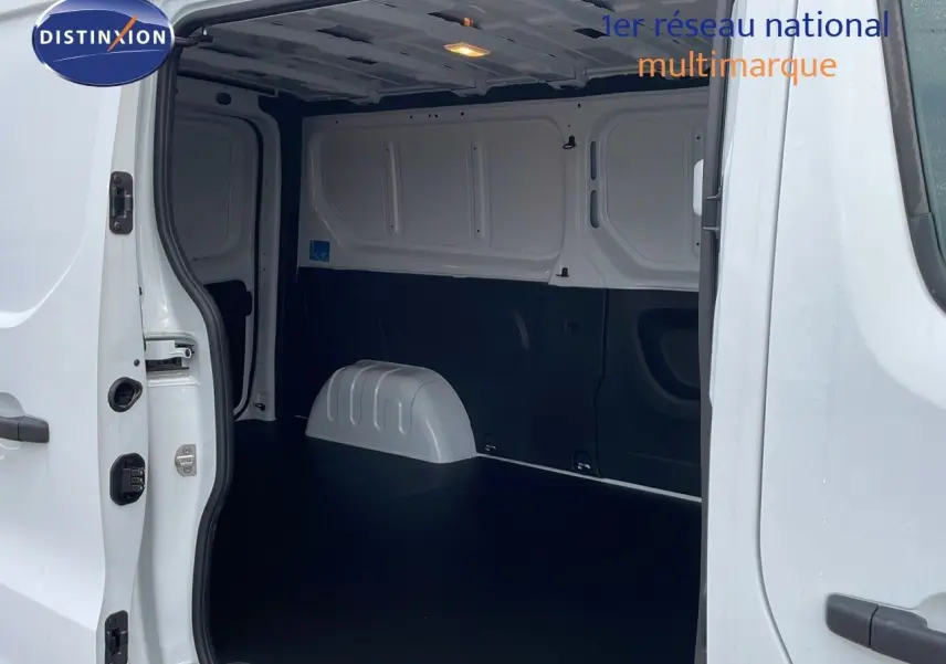 Vue intérieure du fourgon Renault Trafic blanc glacier, montrant l'espace de chargement vide et les portes latérales ouvertes.