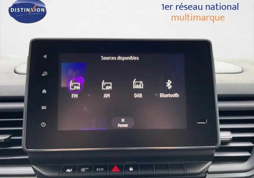 Écran tactile central du tableau de bord du Renault Trafic Fourgon blanc glacier, affichant les sources audio disponibles.