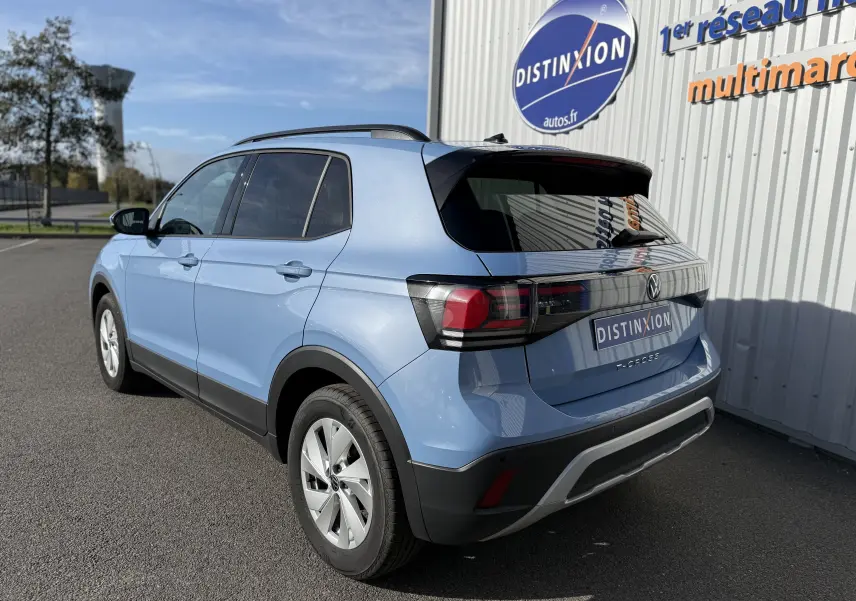 Vue latérale des sièges arrière en tissu gris clair du Volkswagen T-Cross 2024 bleu Sky Metal, intérieur spacieux et sobre.