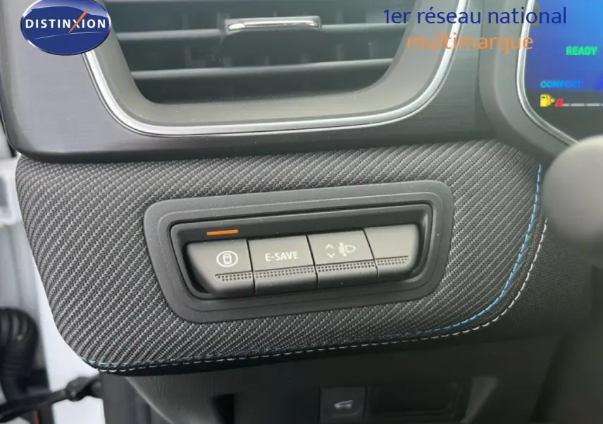 Détail intérieur montrant les boutons de commande sur un panneau en tissu carbone avec surpiqûres bleues dans une Renault Symbioz blanc nacré.