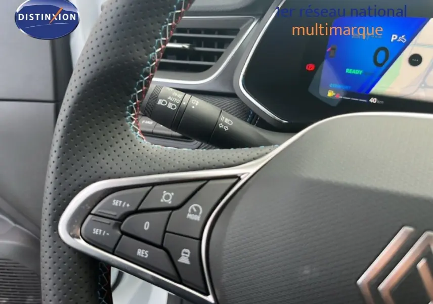 Gros plan sur le volant cuir perforé avec surpiqûres tricolores et commandes intégrées du Renault Symbioz blanc nacré.