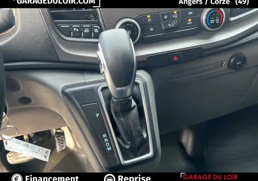 Le levier de vitesse automatique en cuir noir du Ford Transit Custom, avec console et commandes de climatisation visibles.