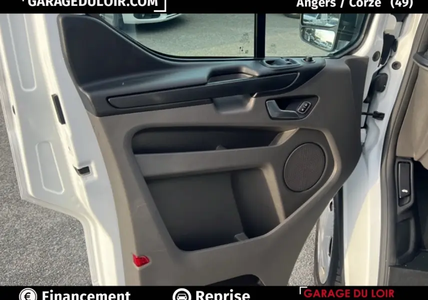Vue rapprochée de la porte avant gauche blanche du Ford Transit Custom Fourgon 2023, avec panneau noir et haut-parleur intégré.