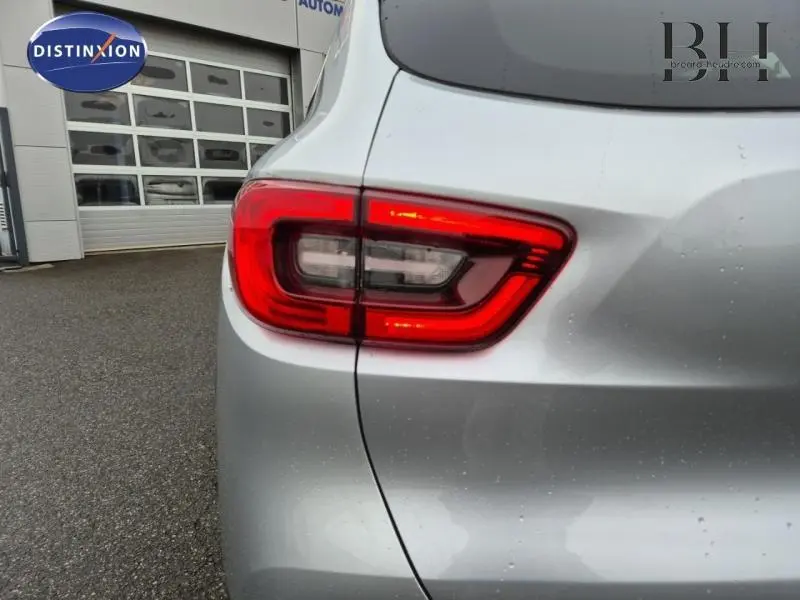 Gros plan sur le feu arrière gauche rouge du Renault Kadjar blanc, avec carrosserie légèrement mouillée.