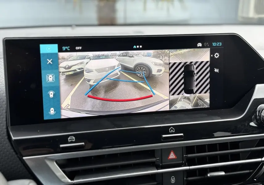 Écran tactile intérieur montrant la caméra 360° avec vue arrière sur une voiture blanche en stationnement.