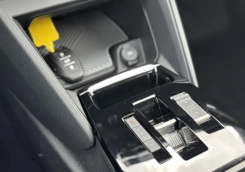 Gros plan sur la console centrale noire brillante de la Citroën C4 PureTech 130, avec sélecteur de mode de conduite.