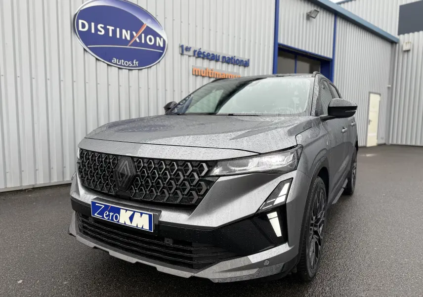 Vue 3/4 avant droit du Renault Austral gris schiste avec toit noir et calandre noire distinctive sous la pluie.