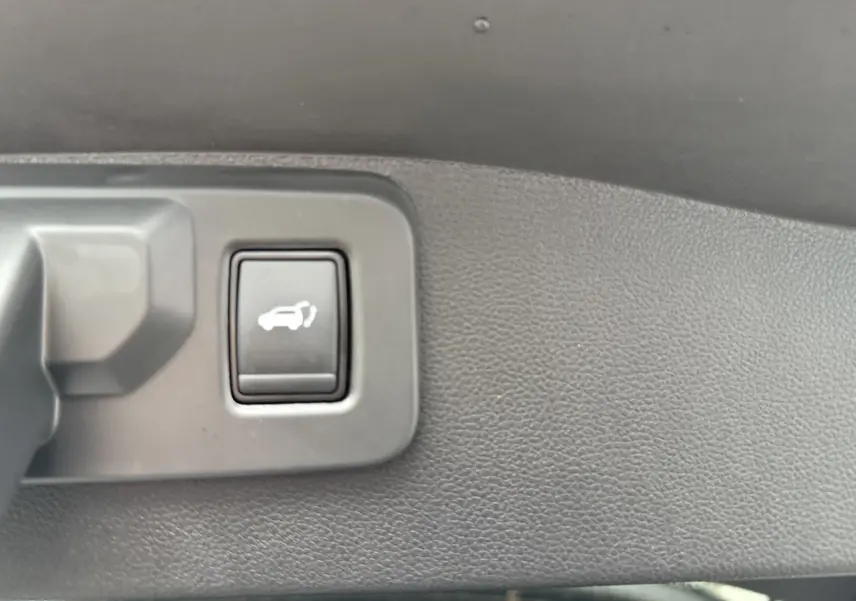 Bouton d'ouverture électrique du hayon sur le panneau intérieur d'un Renault Austral gris schiste toit noir.