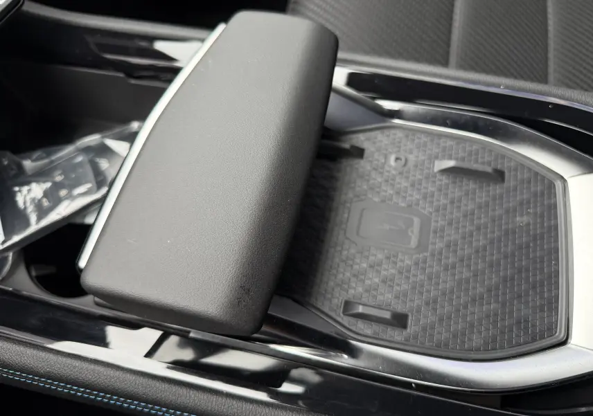 Détail de la console centrale avec accoudoir noir et surface de recharge sans fil texturée dans un Renault Austral 2025.