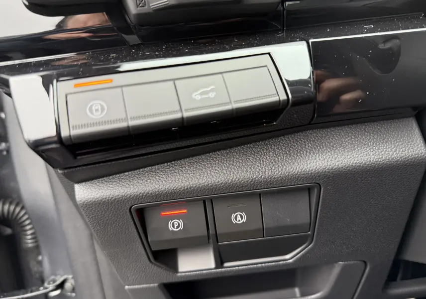 Gros plan sur les commandes du frein de stationnement et ouverture du coffre du Renault Austral 2025, intérieur noir.