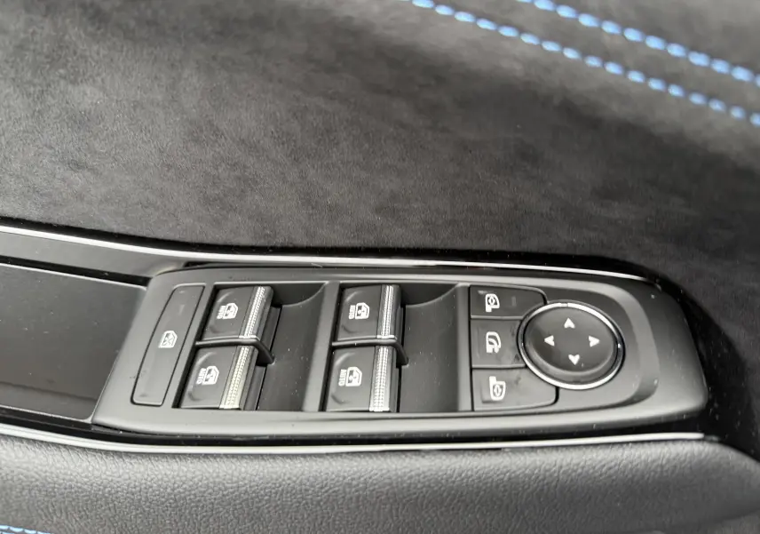 Gros plan sur les commandes des vitres et rétroviseurs côté conducteur du Renault Austral gris schiste avec surpiqûres bleues.