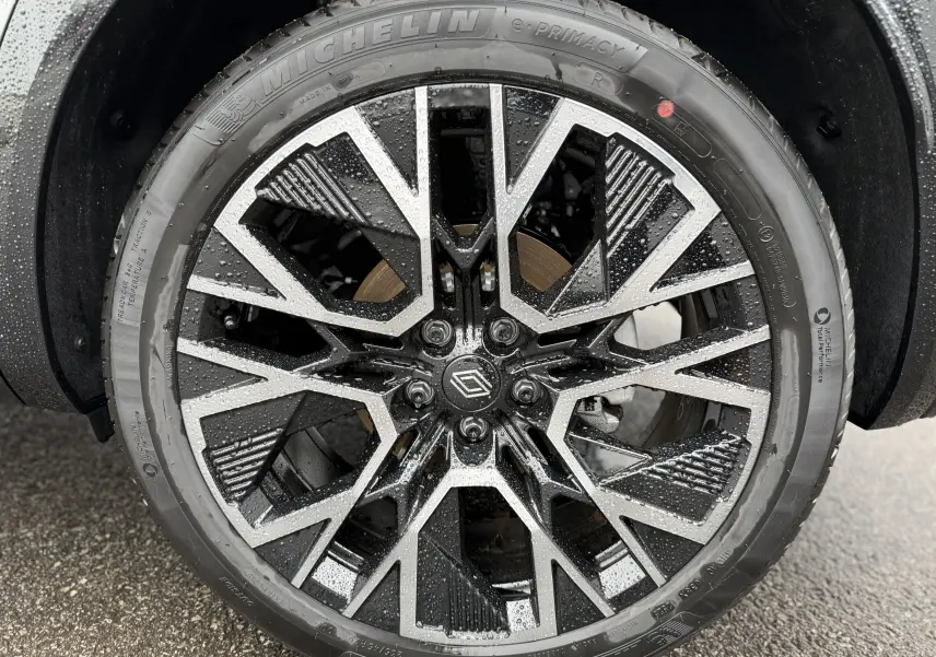 Gros plan sur la jante noire et argentée du Renault Austral 2025, avec pneus Michelin et gouttes d'eau visibles.