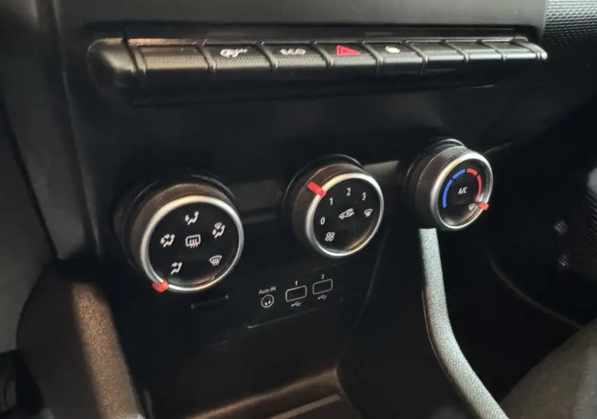 Gros plan sur les commandes de climatisation et ventilation noires du tableau de bord de la Renault Clio Business blanche de 2020.