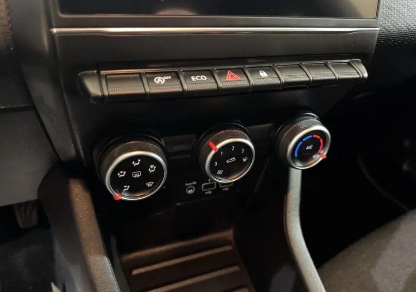 Gros plan sur les commandes de climatisation et boutons de fonction noirs du tableau de bord de la Renault Clio Business blanche.