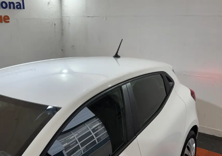 Vue 3/4 arrière droite d'une Renault Clio Business blanche, avec antenne de toit et vitres teintées.