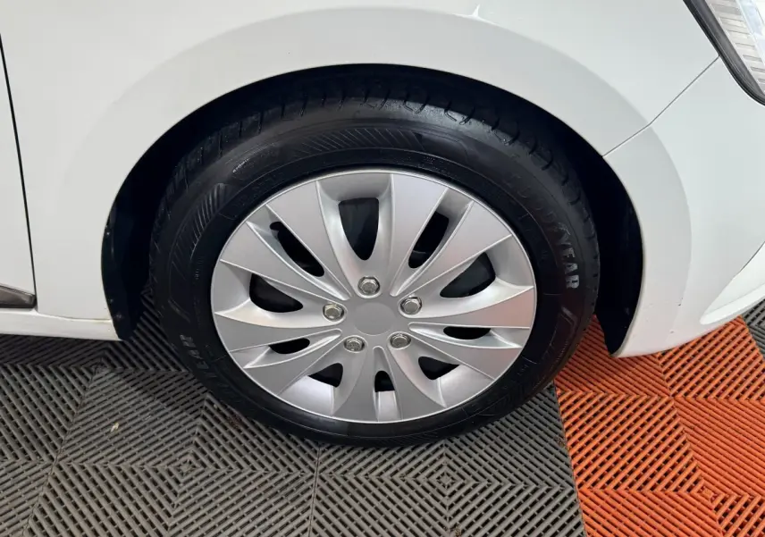 Gros plan sur la roue avant droite de la Renault Clio Business TCe 100 blanche, avec jante en plastique argenté.