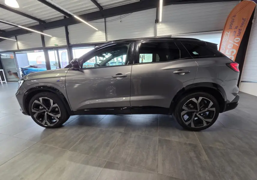 Vue de profil côté gauche d'un Renault Austral gris foncé avec jantes alliage 20 pouces en intérieur showroom.
