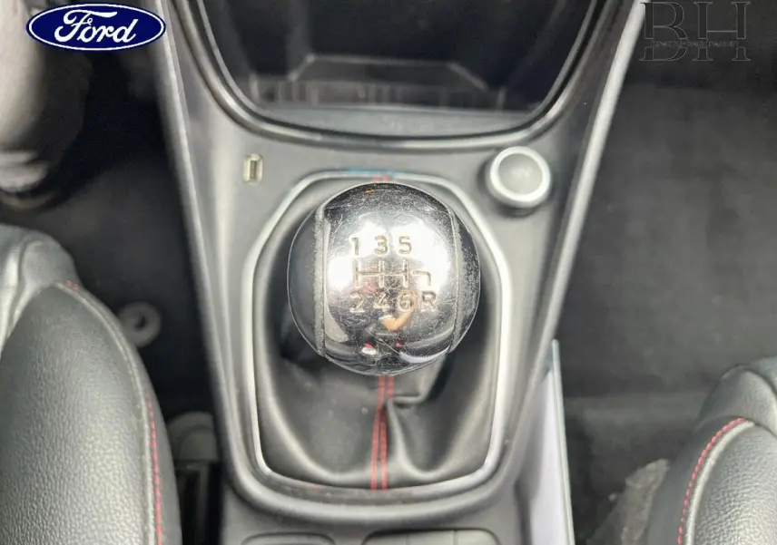 Gros plan sur le levier de vitesses manuel chromé avec surpiqûres rouges, intérieur cuir noir du Ford Puma 2020.