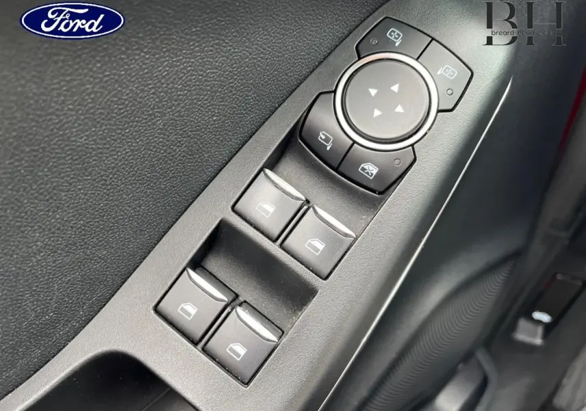 Gros plan sur les commandes des vitres et rétroviseurs côté conducteur d'une Ford Puma rouge Premium Lucid.