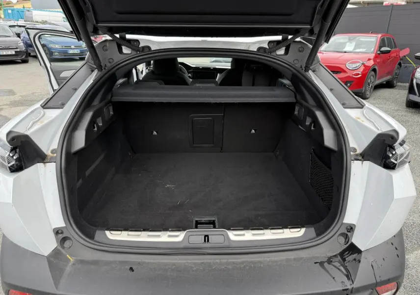 Coffre ouvert vu de l'arrière d'une Peugeot 408 blanche, montrant l'espace de chargement vide et la plage arrière.