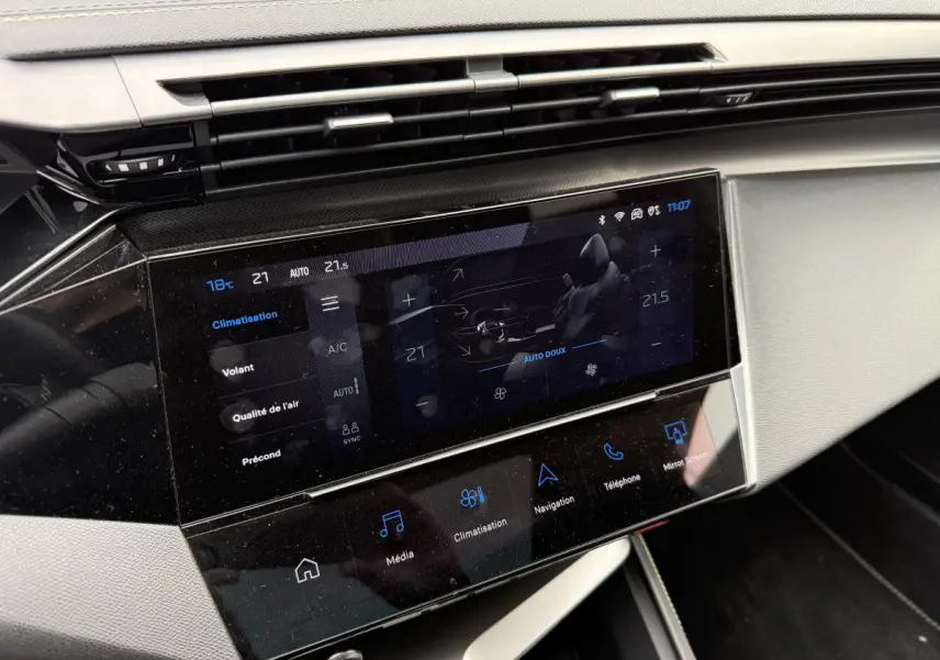 Écran tactile central de la console avant de la Peugeot 408 blanche, affichant les réglages de climatisation.