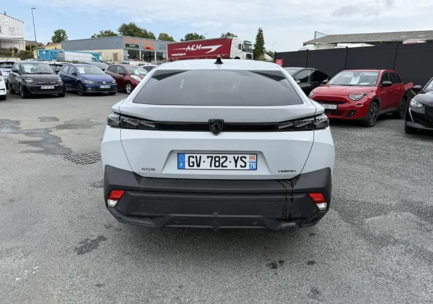 Vue arrière d'une Peugeot 408 blanche hybride avec feux arrière noirs et plaque d'immatriculation française.