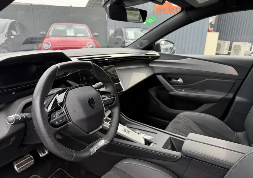 Intérieur de la Peugeot 408 blanc, vue côté conducteur sur le volant GT et la console centrale moderne.