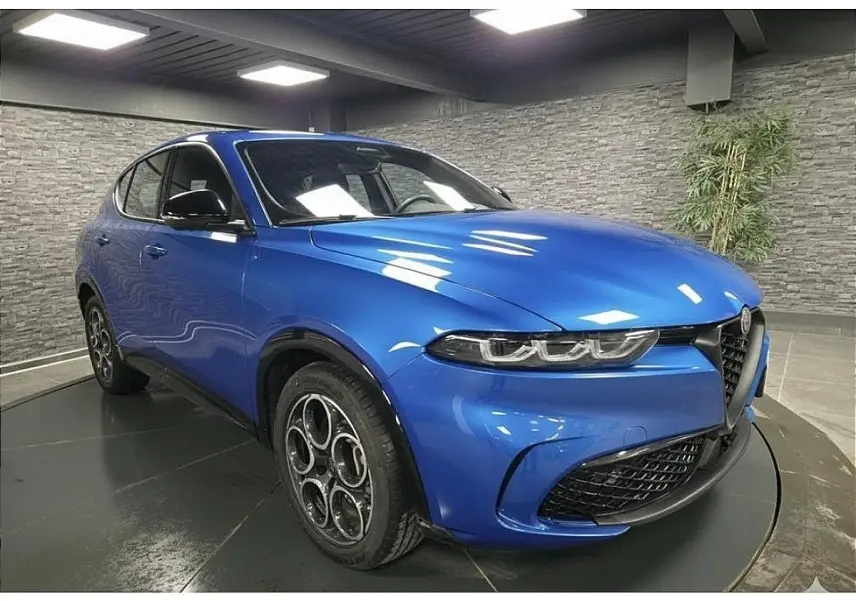 Vue 3/4 avant droite d'une Alfa Romeo Tonale Sprint 2025 bleu métallisé avec jantes alliage et calandre caractéristique.