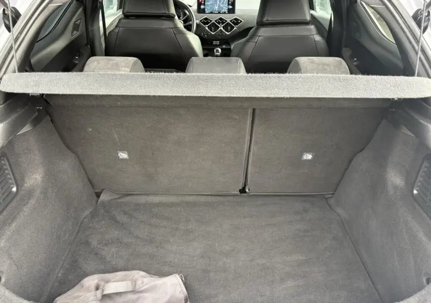 Vue intérieure du coffre et des sièges avant noirs du DS3 Crossback gris Artense, avec tableau de bord et écran GPS visibles.