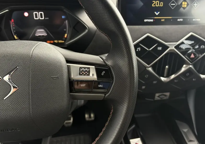 Gros plan sur le volant cuir perforé et les commandes multifonctions du tableau de bord numérique du DS3 Crossback 2021.