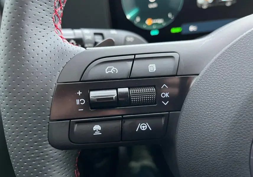 Gros plan sur les commandes multifonctions à gauche du volant perforé avec surpiqûres rouges du Hyundai Tucson 2025 finition N-Line.