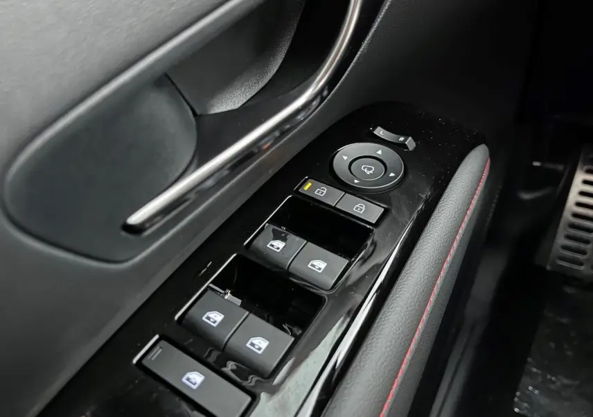 Gros plan sur la commande des vitres et rétroviseurs côté conducteur du Hyundai Tucson 2025 en finition N-Line, intérieur noir avec surpiqûres rouges.