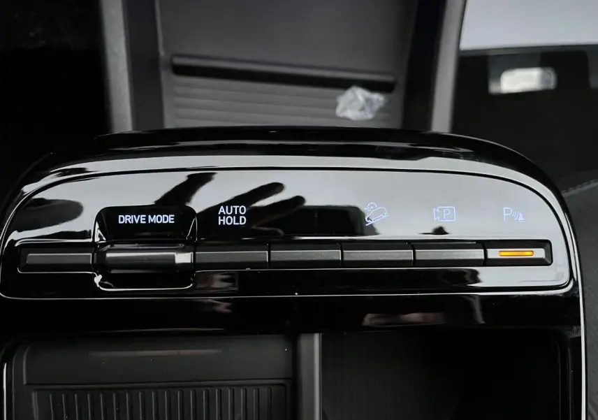 Gros plan sur la console centrale noire brillante du Hyundai Tucson 2025, avec commandes Drive Mode et Auto Hold.
