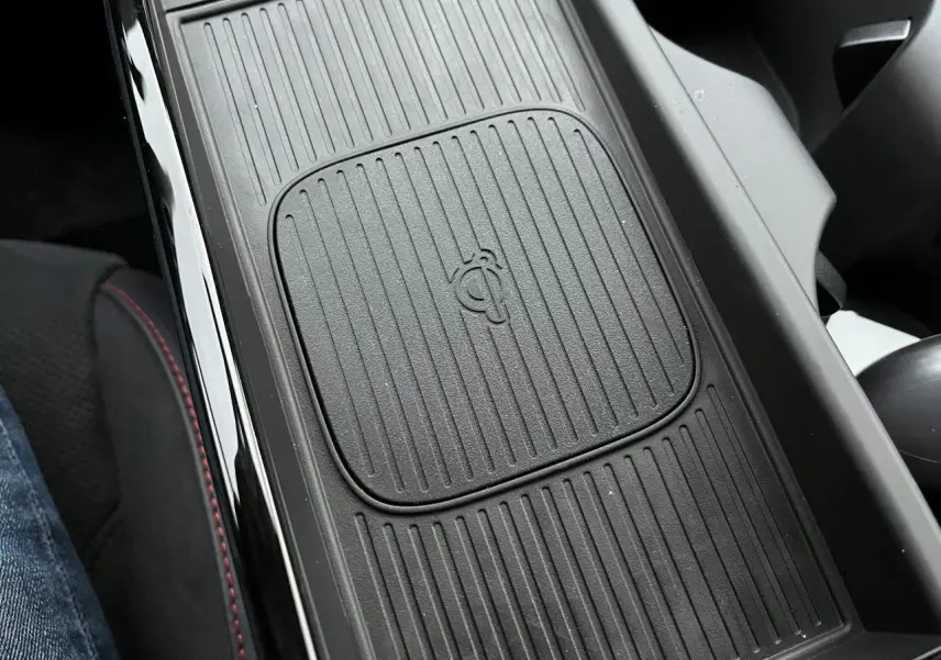 Gros plan sur le chargeur sans fil central noir du Hyundai Tucson 2025, finition N-Line Creative, intérieur avec surpiqûres rouges.