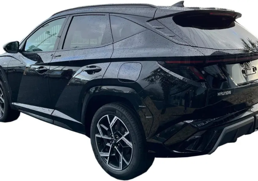 Vue 3/4 arrière droite du Hyundai Tucson 2025 hybride en noir Abyss, avec jantes alliage et feux arrière LED continus.