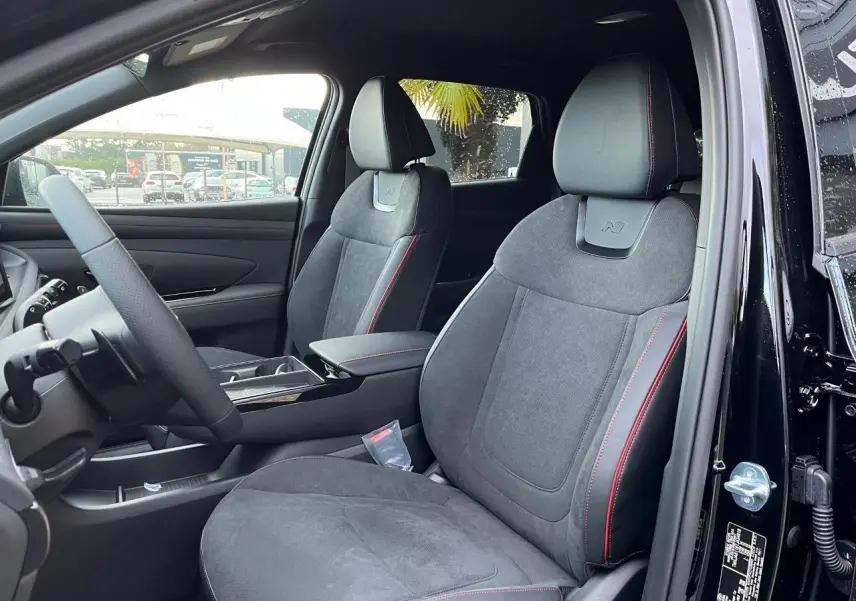 Vue intérieure côté conducteur du Hyundai Tucson 2025 noir Abyss, sièges en cuir et alcantara avec surpiqûres rouges et logo N.